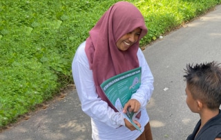 A woman in a hijab shows a student an educational poster